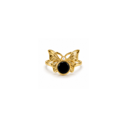 Gold-coloured butterfly ring with detailed wings, a round black centre and small white accent on a white background.